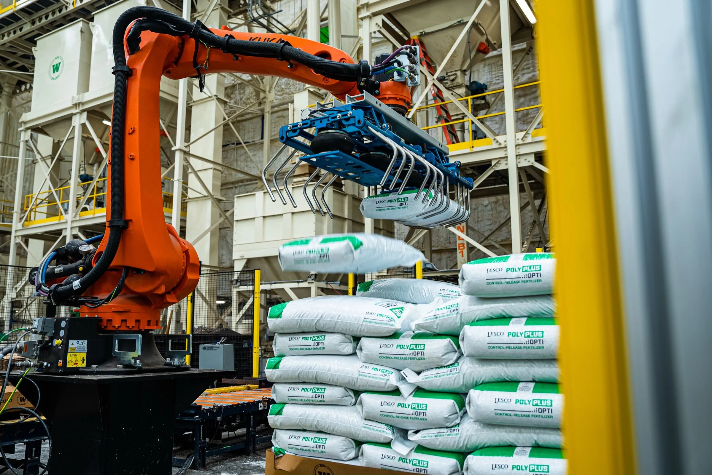 An orange robot arm stacking bags on a pallet at the Moore Haven bag plant