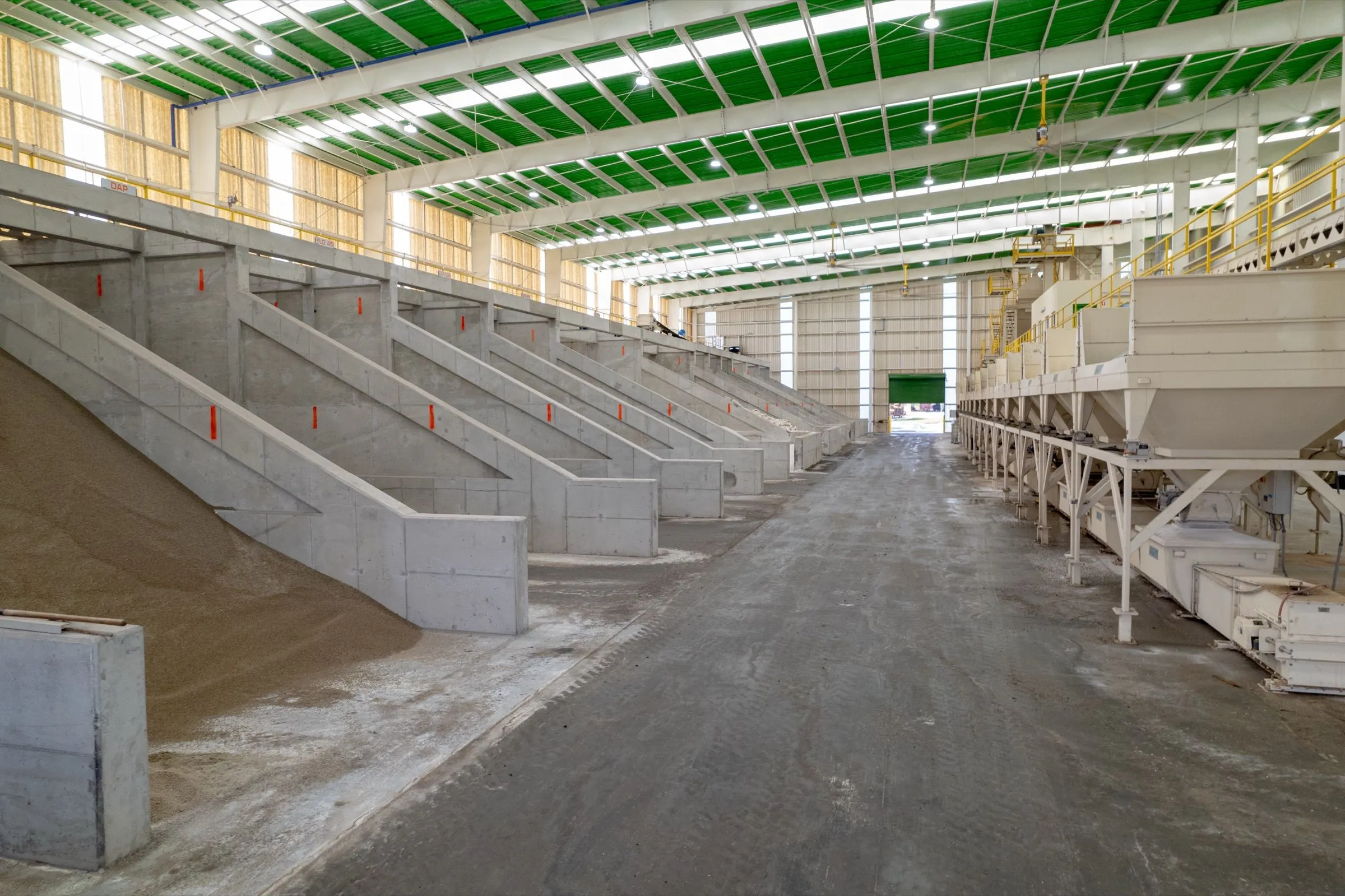 A long row of product bins under the green roof of the Moore Haven bag plant