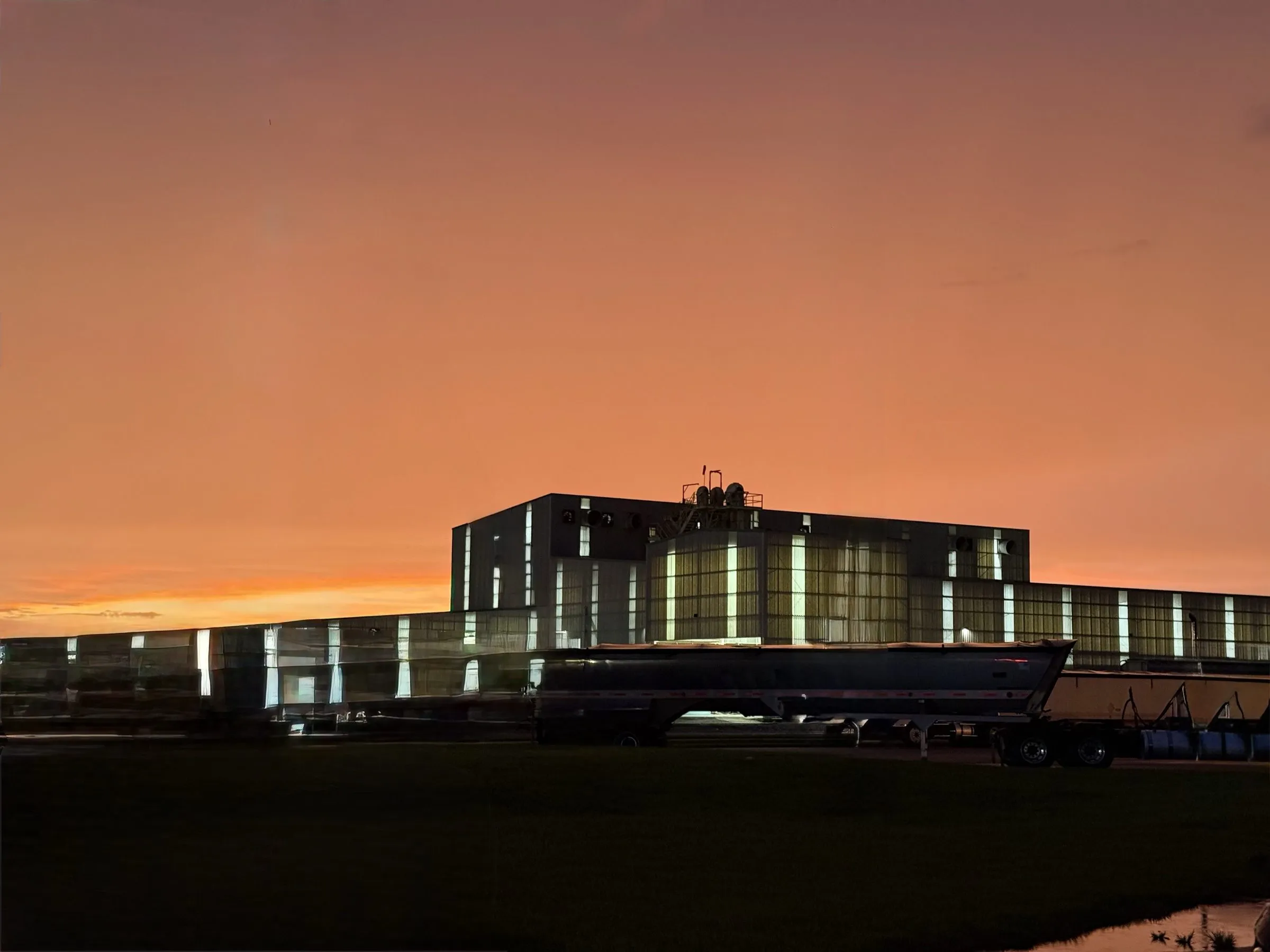 The Moore Haven bag plant at dusk, its windows lit against an orange sky